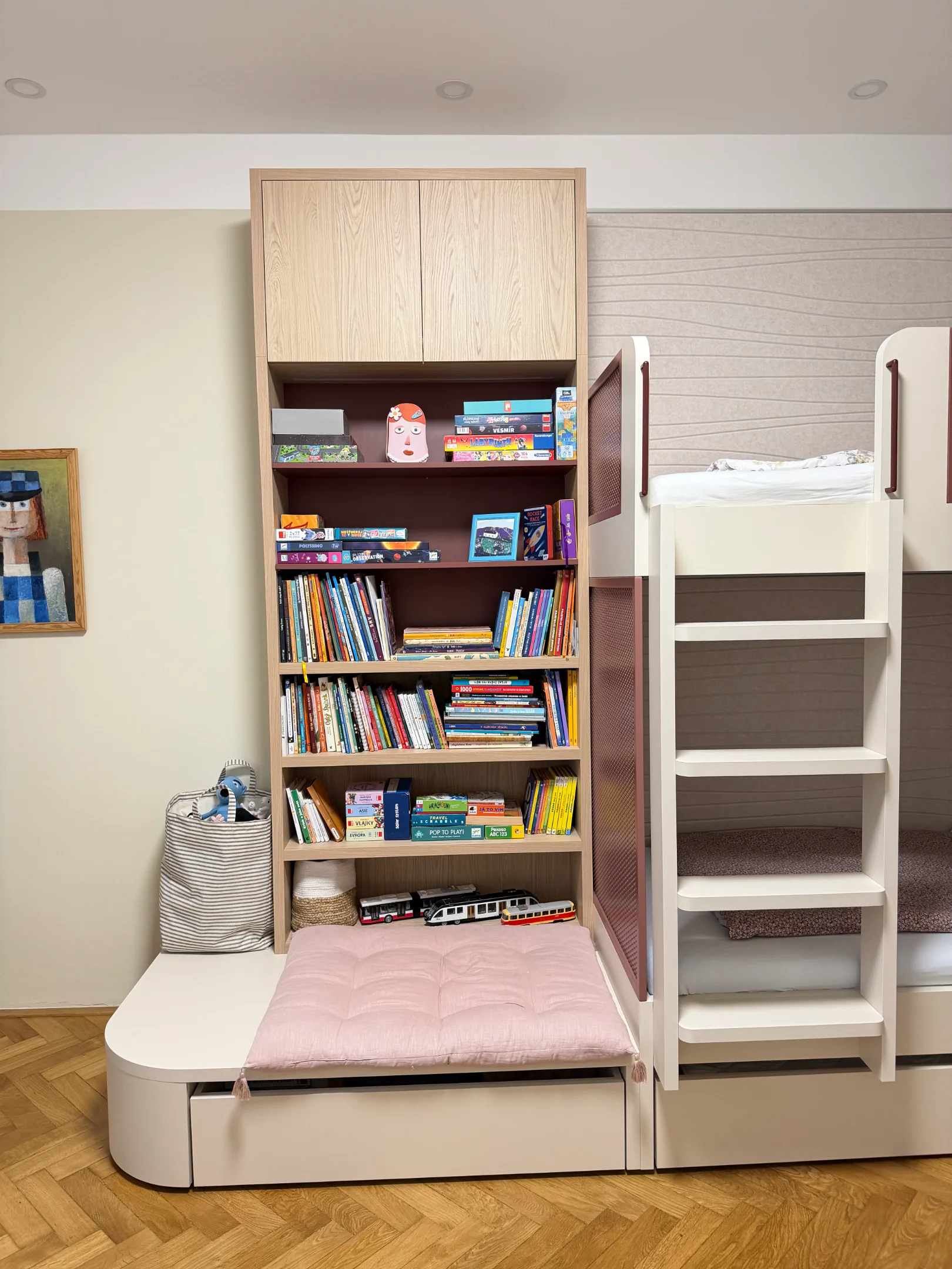 Dětský pokoj s patrovou postelí a knihovnou plnou knih.